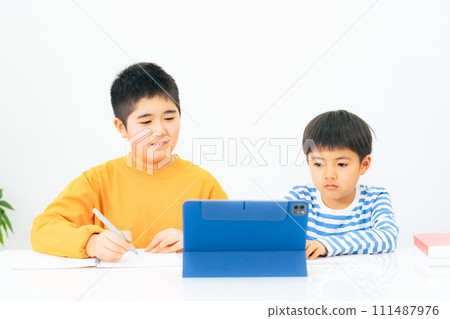 Elementary school siblings taking online classes on tablets Elementary school siblings taking online classes on tablets 111487976