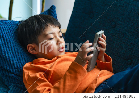 小學生躺在沙發上使用智慧型手機 小學生躺在沙發上使用智慧型手機 111487993