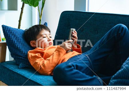 小學生躺在沙發上使用智慧型手機 小學生躺在沙發上使用智慧型手機 111487994