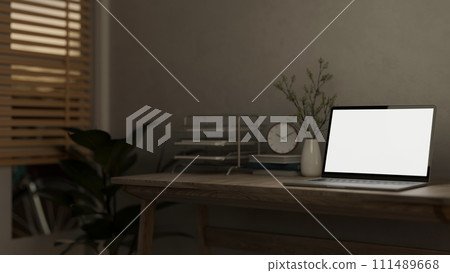 A laptop computer mockup and decor are placed on a hardwood desk in a minimally cozy home office. 111489668