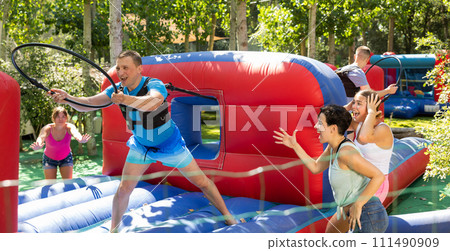 Happy man competing with friends in collect hoops on inflatable arena 111490909