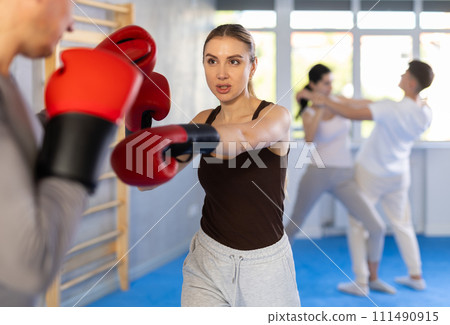 Young girl training boxing with partner during sports classes Young girl training boxing with partner during sports classes 111490915