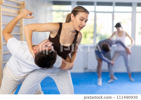 Young girl applying throwing technique on her opponent in sports hall Young girl applying throwing technique on her opponent in sports hall 111490930