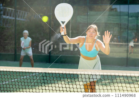 Young woman in skirt playing padel tennis on court 111490968