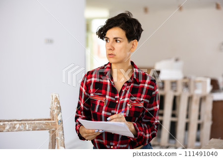 Focused girl making notes while working on renovation her house Focused girl making notes while working on renovation her house 111491040