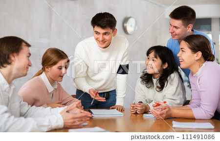 Young male tutor teaching group of students in college 111491086