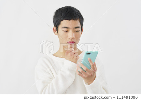 一個男孩拿著智慧型手機思考，白色背景 111491090