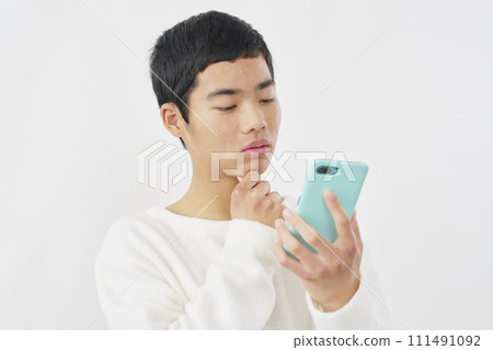 一個男孩拿著智慧型手機思考，白色背景 111491092