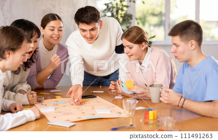 Young guys and girls playing board game together 111491263