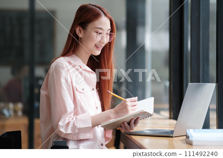 Young collage student using computer and mobile device studying online. Young collage student using computer and mobile device studying online. 111492240