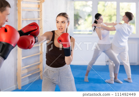 Girl in boxing gloves learns to box under the guidance of trainer in gym 111492449