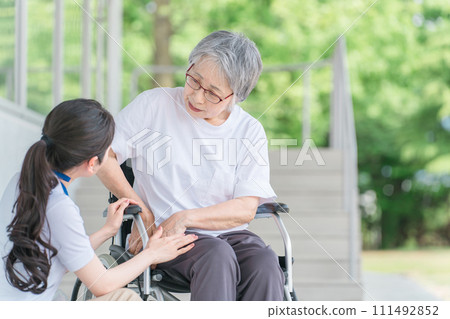 An elderly person in a wheelchair with hip pain and a female caregiver (rheumatism/artificial joint) An elderly person in a wheelchair with hip pain and a female caregiver (rheumatism/artificial joint) 111492852