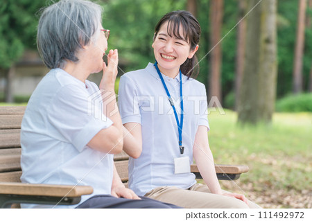 Smiling female nursing care staff and elderly people talking in the park (talking and having fun) Smiling female nursing care staff and elderly people talking in the park (talking and having fun) 111492972