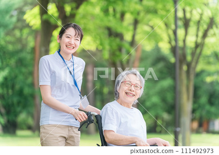 Elderly people in wheelchairs walking in the park and women who are caregivers, nurses, physical therapists, and exercise instructors Elderly people in wheelchairs walking in the park and women who are caregivers, nurses, physical therapists, and exercise instructors 111492973