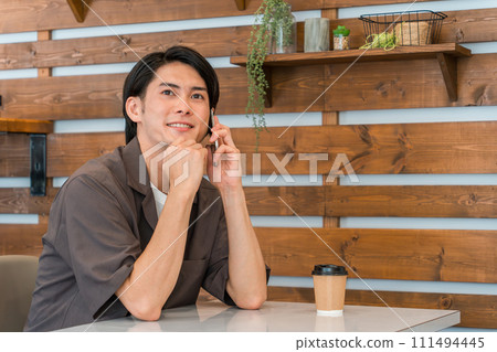 A young Asian man calling using a smartphone at a cafe, home, etc. 111494445