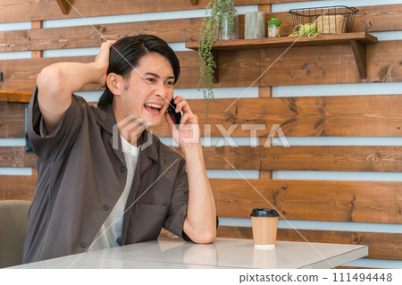 年輕的亞洲男子在咖啡館打電話(無意錯誤/人為錯誤) 年輕的亞洲男子在咖啡館打電話(無意錯誤/人為錯誤) 111494448