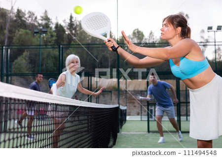 Sportive girl with racquet playing padel in court Sportive girl with racquet playing padel in court 111494548