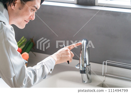 A businessman in work clothes from a plumber, equipment company, remodeler, or construction company checking the water supply A businessman in work clothes from a plumber, equipment company, remodeler, or construction company checking the water supply 111494799