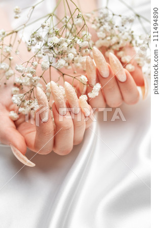Female Hands on a white silk background with beautiful pearl manicure.Hands on a brown background and beautiful pearl manicure Female Hands on a white silk background with beautiful pearl manicure.Hands on a brown background and beautiful pearl manicure 111494890