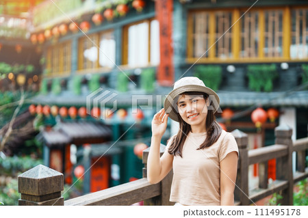 woman traveler visiting in Taiwan, Tourist with hat sightseeing in Jiufen Old Street village with Tea House background. landmark and popular attractions near Taipei city . Travel and Vacation concept 111495178
