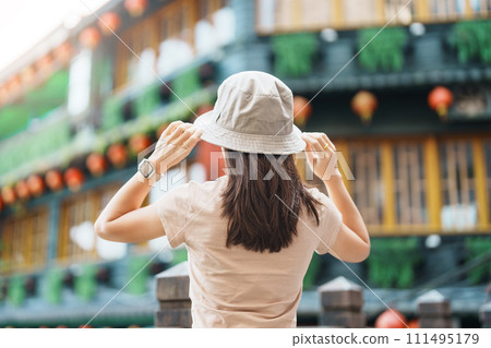 woman traveler visiting in Taiwan, Tourist with hat sightseeing in Jiufen Old Street village with Tea House background. landmark and popular attractions near Taipei city . Travel and Vacation concept 111495179