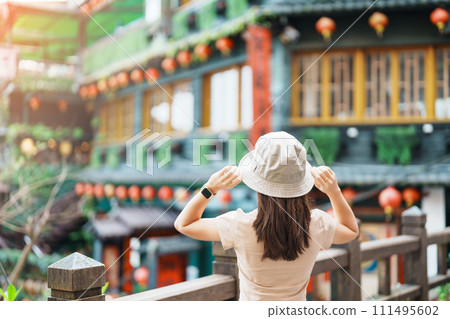 woman traveler visiting in Taiwan, Tourist with hat sightseeing in Jiufen Old Street village with Tea House background. landmark and popular attractions near Taipei city . Travel and Vacation concept 111495602