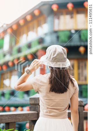woman traveler visiting in Taiwan, Tourist with hat sightseeing in Jiufen Old Street village with Tea House background. landmark and popular attractions near Taipei city . Travel and Vacation concept 111495631