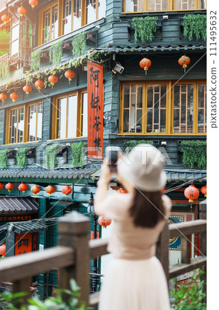 woman traveler visiting in Taiwan, Tourist taking photo and sightseeing in Jiufen Old Street village with Tea House background. landmark and popular attractions near Taipei city. Travel concept 111495632