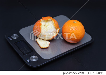 Electronic kitchen scale with two tangerines, calorie counting. Electronic kitchen scale with two tangerines, calorie counting. 111496095