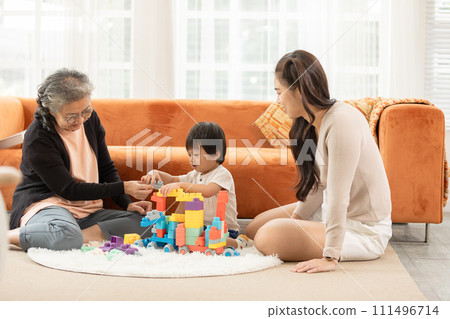 Heartwarming scene as baby toddler enthusiastically plays with stacking blocks, bringing joy to the faces of both their loving grandmother and mother in delightful family bonding moment. love concept Heartwarming scene as baby toddler enthusiastically plays with stacking blocks, bringing joy to the faces of both their loving grandmother and mother in delightful family bonding moment. love concept 111496714