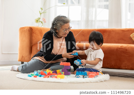 Heartwarming scene as baby toddler enthusiastically plays with stacking blocks, bringing joy to the faces of grandmother in delightful family bonding moment. love and good moment concept 111496720