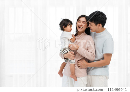 cheerful father and mother holding and hugging with toddler baby on white window background. happy family cheerful father and mother holding and hugging with toddler baby on white window background. happy family 111496941
