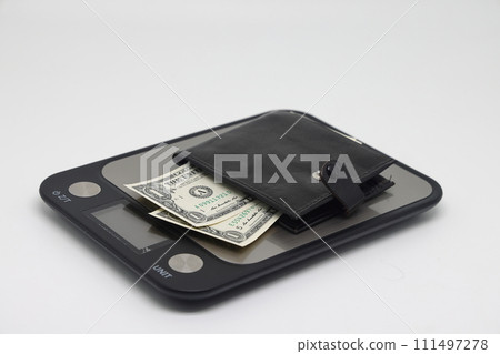 Wallet with banknotes on electronic kitchen scales. Icheta symbol and family finance planning. 111497278
