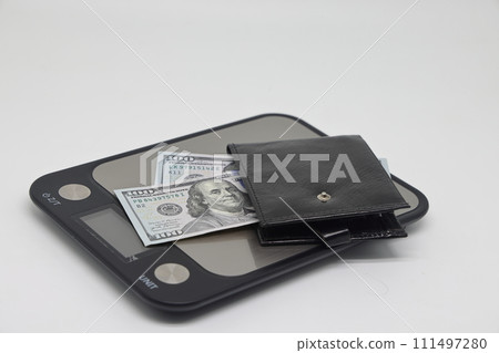 Wallet with banknotes on electronic kitchen scales. Icheta symbol and family finance planning. 111497280