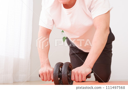 一個男人用腹部肌肉滾筒進行肌肉訓練 一個男人用腹部肌肉滾筒進行肌肉訓練 111497568