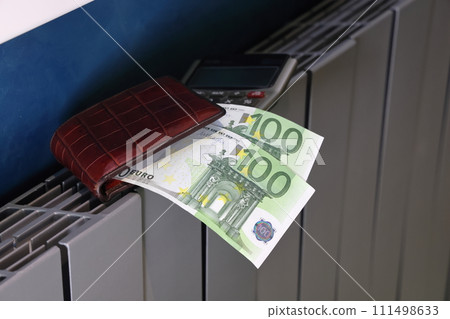 Calculator, wallet and banknotes lie on the radiator of the heating system, the cost of heat Calculator, wallet and banknotes lie on the radiator of the heating system, the cost of heat 111498633