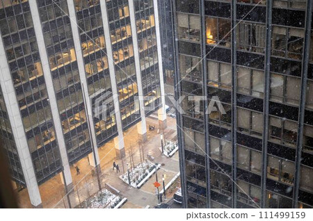 Aerial view of snow falling over urban cityscape pedestrians buildings Aerial view of snow falling over urban cityscape pedestrians buildings 111499159