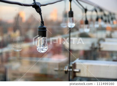 String of festive lights on NYC rooftop terrace overlooking bokeh city String of festive lights on NYC rooftop terrace overlooking bokeh city 111499160