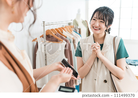 A woman and a shop clerk shopping using smartphones, smartphone payments, and online payments 111499370