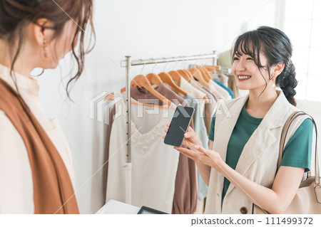 一名婦女和一名店員使用智慧型手機購物、智慧型手機支付和線上支付 111499372