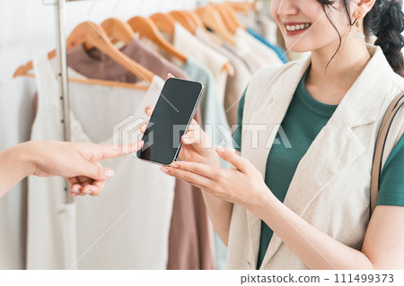 一名婦女和一名店員使用智慧型手機購物、智慧型手機支付和線上支付 111499373