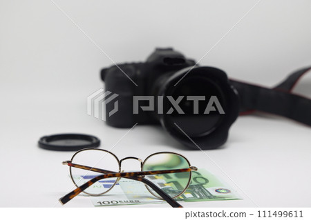Office desk workplace with camera, glasses and banknotes. Earnings on photo stocks. 111499611