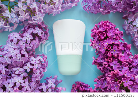 Antiperspirant deodorant roll-on bottle and purple lilac flowers a lot on blue background. Packaging mockup close-up Antiperspirant deodorant roll-on bottle and purple lilac flowers a lot on blue background. Packaging mockup close-up 111500153