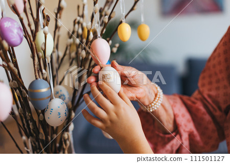 Close up of decorating pussy willows branches, putting easter eggs on them. 111501127