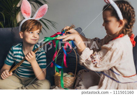 Boy holding handmade whip, made of willow branches, decorated with ribbons. Unique easter custom from slovakia, gently whipping woman and tranditional verses and easter wishes. 111501160