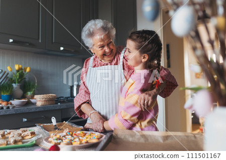 Grandmother with grandaughter preparing traditional easter meals, baking cakes and sweets. Passing down family recipes, custom and stories. 111501167