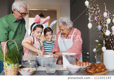 Grandparents with grandchildren preparing traditional easter meals, baking cakes and sweets. Passing down family recipes, custom and stories. 111501197