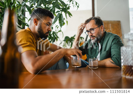 Best friends, supporting each other, drinking whiskey and talking. Discussing problems and drowning sorrows in alcohol. Concept of male friendship, bromance. 111501814