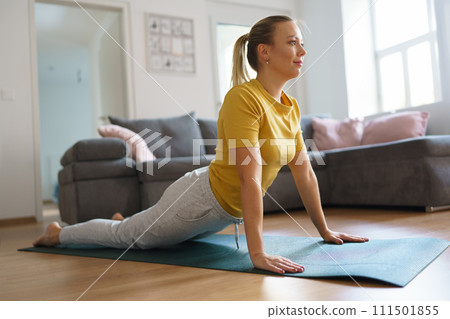 Woman exercising at home, stretching her body. Solo home workout and meditation, morning or evening workout routine. 111501855