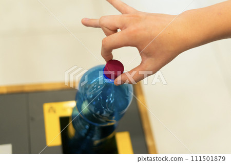 Close up hand throwing empty plastic water bottle into recycling bin, recycle rubbish Close up hand throwing empty plastic water bottle into recycling bin, recycle rubbish 111501879